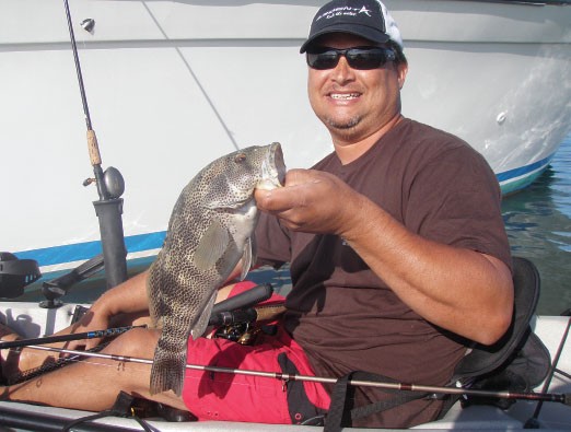 Deckhand readying small kite on short rod for fishing live bait